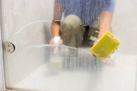 Foto de Sostenga la esponja sobre lavar el vidrio de la ventana - Imagen libre de derechos