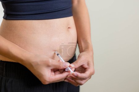Photo for Patient is injecting hormones to abdomen with syringe. - Royalty Free Image