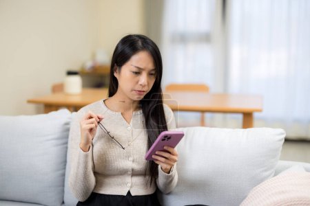 Téléchargez les photos : Femme souffrant de fatigue oculaire en essayant de lire sur un téléphone portable à la maison - en image libre de droit