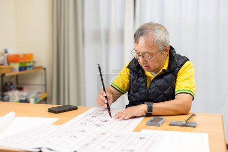 Photo for Asian old man practice Chinese calligraphy character at home - Royalty Free Image