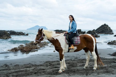 Femme touristique monter à cheval à côté de la plage de la mer