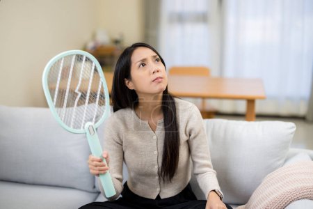 Téléchargez les photos : Woman use mosquito swatter at home - en image libre de droit