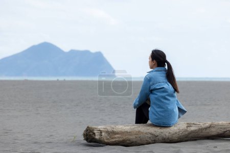 Femme assise sur la plage et regarder le Guishan à Yilan