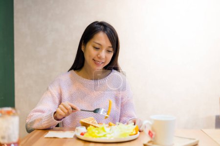Téléchargez les photos : Femme profiter de son repas au café - en image libre de droit