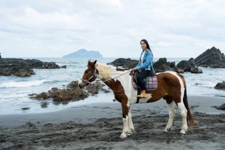 Femme touristique monter à cheval à côté de la plage de la mer