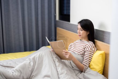 Téléchargez les photos : Femme a lu le cahier sur le lit - en image libre de droit