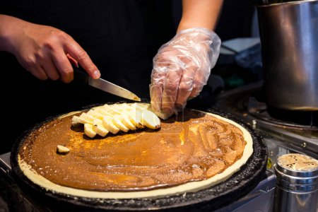 Foto de Comida callejera haciendo pastel de crepe con chocolate y plátano - Imagen libre de derechos
