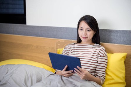 Téléchargez les photos : Femme montre sur tablettes numériques ordinateur sur le lit - en image libre de droit