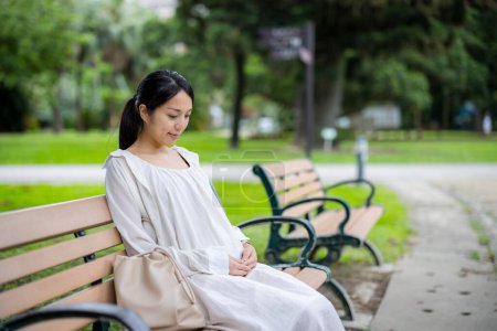 Foto de Mujer embarazada sentarse en la silla en el parque - Imagen libre de derechos