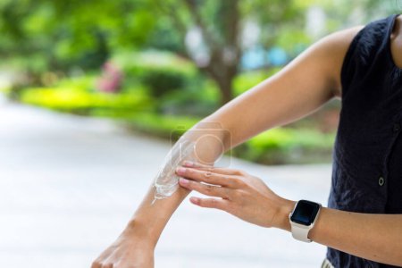 Téléchargez les photos : Femme appliquée crème solaire sur sa main à l'heure d'été - en image libre de droit