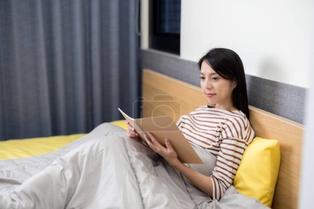 Photo for Woman read on notebook on bed at home - Royalty Free Image