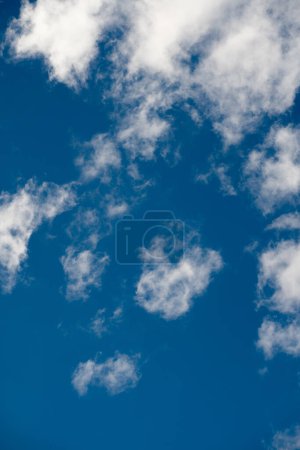 Soft, cotton-like clouds gracefully float across a deep blue sky, creating a stunning contrast and a peaceful, airy canvas that invokes a sense of calm and expansiveness.