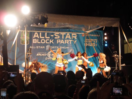 Foto de Waikiki - 26 de enero de 2013: Las animadoras de la NFL bailan en el escenario en la All-Star Block Party mientras la gente graba el baile en sus teléfonos durante la semana ProBowl en Waikiki, Hawaii. Llevan los uniformes de sus respectivos equipos y actúan para el - Imagen libre de derechos