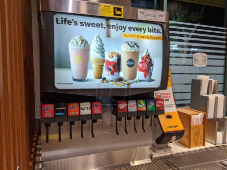 Photo for Honolulu, Hawaii, USA - March 14, 2020: Coca-Cola Classic Soda Fountain Station at McDonald's with Fanta, Powerade, Water, Dr Pepper, Sprite and ad for McCafe Drinks and Desserts next to Straws, Napkins, and Lids. - Royalty Free Image