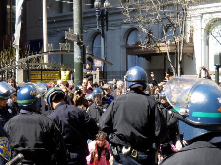 Photo for San Francisco - March 19, 2008:  San Francisco police officers arrest an old lady protester on March 19, 2008. The protester is part of a group of anti-war demonstrators who are blocking traffic in the city's financial district. The image captures th - Royalty Free Image