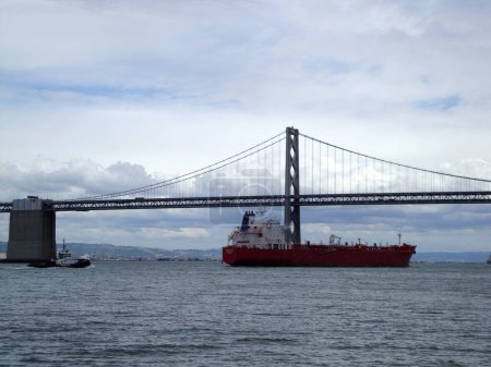Foto de San Francisco - 31 de marzo de 2010: El envío del mundo: Un barco de carga masiva navega bajo el puente de la bahía con la ayuda de un remolcador. - Imagen libre de derechos