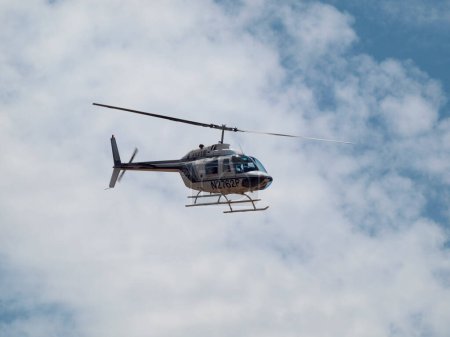 Foto de Nevada - 29 de julio de 2011: Helicóptero blanco y azul volando en el cielo con nubes blancas y nubladas. - Imagen libre de derechos