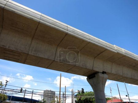 Foto de Honolulu - 22 de junio de 2016: la vista bajo un puente ferroviario para el HART Skyline, un sistema de tránsito rápido en construcción en Honolulu, Hawái. Situado en una calle de la ciudad concurrida con tiendas y restaurantes. Mostrando el contraste entre el puente ferroviario moderno - Imagen libre de derechos