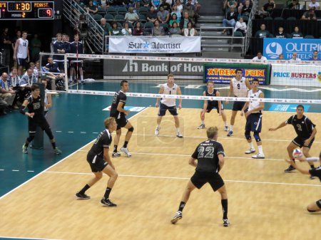 Photo for Honolulu - January 10, 2014: College Volleyball players compete on an indoor court with the scoreboard visible. - Royalty Free Image