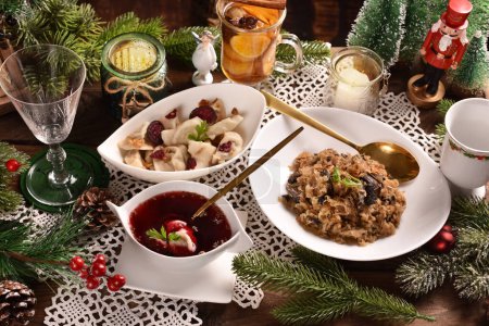Photo for Christmas Eve's red borscht soup with mushroom filled ravioli and beet chips and sauerkraut with mushrooms on festive table - Royalty Free Image