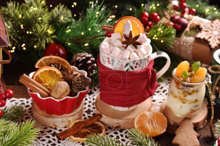 A cup of Christmas coffee or hot chocolate with marshmallows and mini jar of yogurt with gingerbread cookies,tangerine and passion fruit