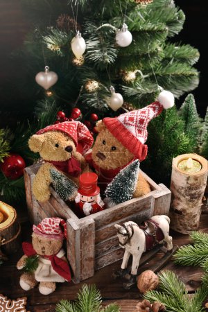 Photo for Christmas still life with old teddy bears in Santa caps in wooden box and other toys on the table in rustic style - Royalty Free Image