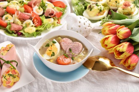 Easter table with traditional soup white borscht with sausage, fresh salads and eggs with mayonnaise