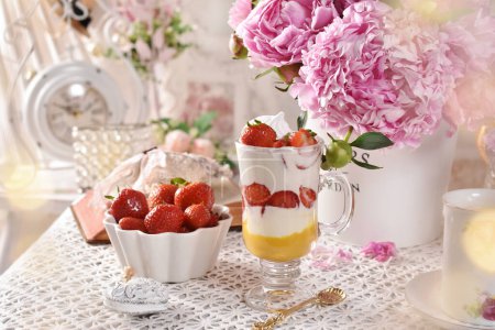 Téléchargez les photos : Dessert aux fraises et à la crème et fruits frais sur la table dans un style vintage avec un bouquet de pivoines roses - en image libre de droit