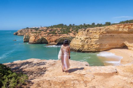 Foto de Benagil, Portugal - 03 de abril de 2024: Turista admirando los acantilados y la cueva cerca de Benagil en la región del Algarve, Portugal - Imagen libre de derechos