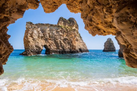 Foto de Pequeña, paradisíaca y difícil acceso a la playa fotografiada desde el interior de una cueva, cerca de Portimao en la región del Algarve de Portugal - Imagen libre de derechos