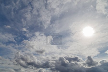Photo for Blue sky with sun and mixed clouds on different layers, above horizon view. - Royalty Free Image