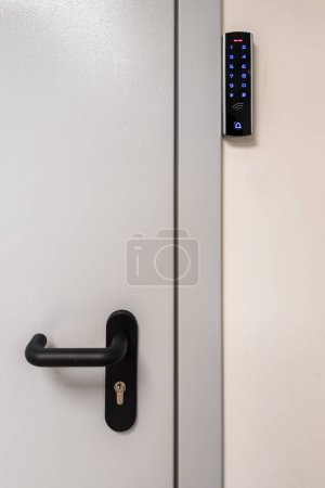 Foto de Puerta metálica gris con mango negro y sensor táctil digital cerradura RFID. - Imagen libre de derechos