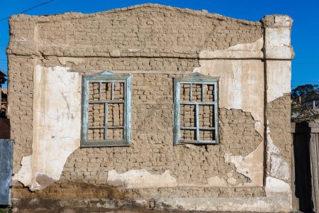 Téléchargez les photos : Vieux mur de briques d'air de maison adobe avec deux cadres de fenêtre en bois intégrés et les restes de plâtre pelés texture plate. - en image libre de droit