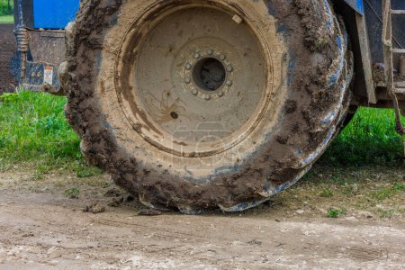 verschmutztes Doppelrad eines großen landwirtschaftlichen Traktors auf Feldweg an Sommertagen, Nahaufnahme