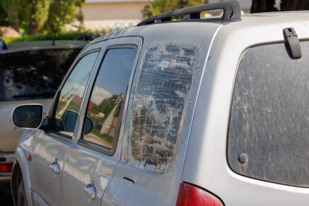 cuarto de ventana trasera de SUV plateado roto y cubierto con varias capas de cinta adhesiva transparente, rápida fijación temporal barata, vista de primer plano