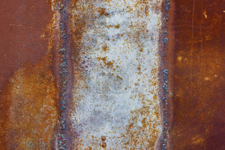 Primer plano de una superficie metálica soldada oxidada de color marrón con tonalidad amarillenta y naranja y pátina ámbar.