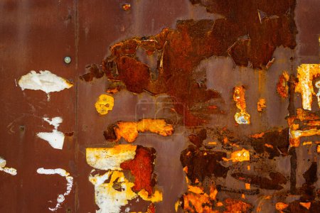 Photo for Close up of a brown rusted sheet metal surface with leftovers of peeled off paper advertisements. - Royalty Free Image