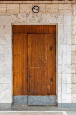 vieja puerta de madera del edificio público soviético en una pared hecha de roca de concha y mármol, la parte inferior de la puerta está cubierta con chapas de acero galvanizadas