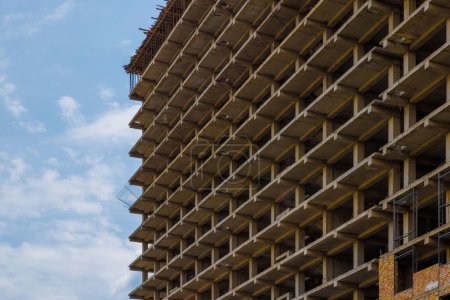 Photo for High-rise apartment building under construction against a blue sky with simple square reinforced concrete urban design. - Royalty Free Image