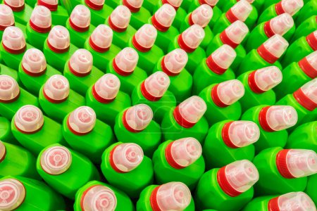 Green bottles of household toilet cleaning bleach gel with sodium hypochlorite, NaOCl with red and transparent caps. Full-frame closeup background with high angle view.