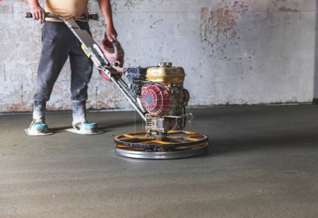 Construction worker in a room that grind the concrete surface