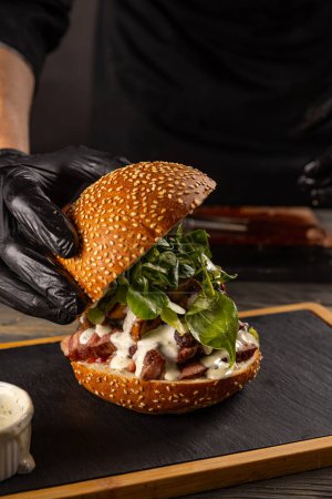 Foto de Primer plano de la mano del chef preparando una deliciosa hamburguesa de carne - Imagen libre de derechos
