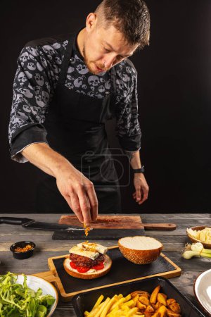 Foto de Chef poniendo cebolla seca en la hamburguesa. Concepto de comida rápida - Imagen libre de derechos