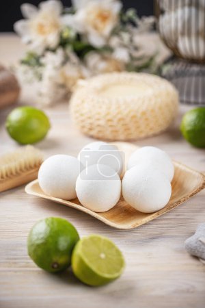 Spa essentials with natural bath bombs and lime on wooden surface
