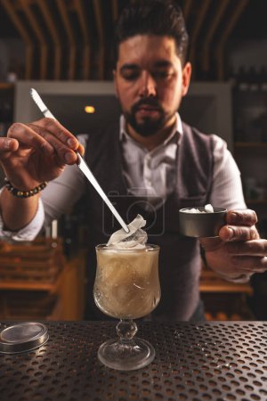 Focused mixologist meticulously adding garnish to an elegant cocktail at a bar