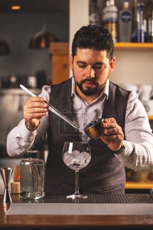 Focused male bartender carefully measures ingredients for a sophisticated mixed drink