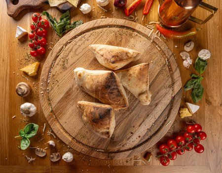 Photo for Rustic homemade calzones on wooden cutting board, top view - Royalty Free Image