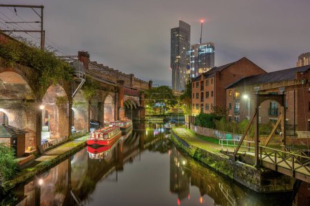 Photo for Castlefield in Manchester, UK, at night, with a modern skyscraper in the back - Royalty Free Image