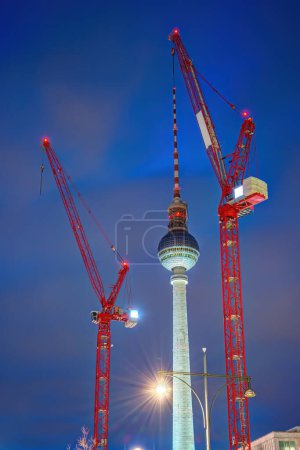 Téléchargez les photos : La célèbre tour de télévision de Berlin au crépuscule avec deux grues de construction rouge - en image libre de droit