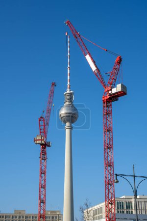 The famous Television Tower of Berlin with two red construction cranes